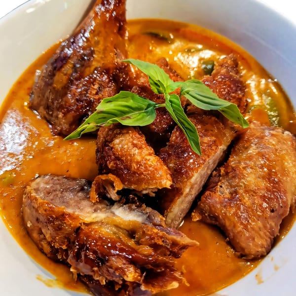 Crispy duck in a rich red curry sauce, garnished with fresh basil, from Nakama Sushi Thai.