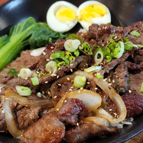 Nakama Sushi Thai's beef dish with onions, scallions, sesame seeds, bok choy, and hard-boiled eggs.