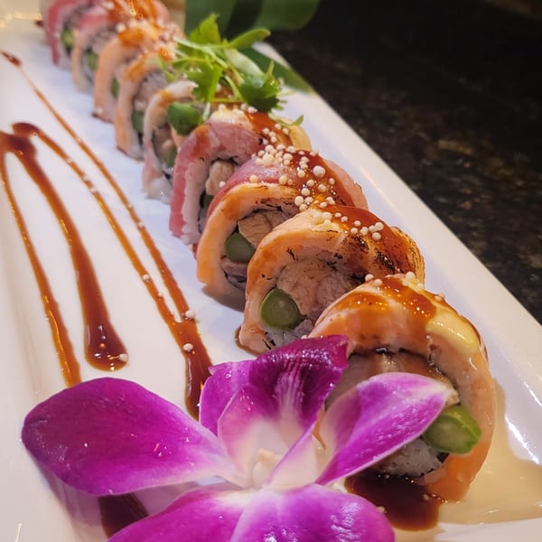 Nakama Sushi Thai's sushi rolls with sauce, crispy toppings, and a purple orchid garnish.