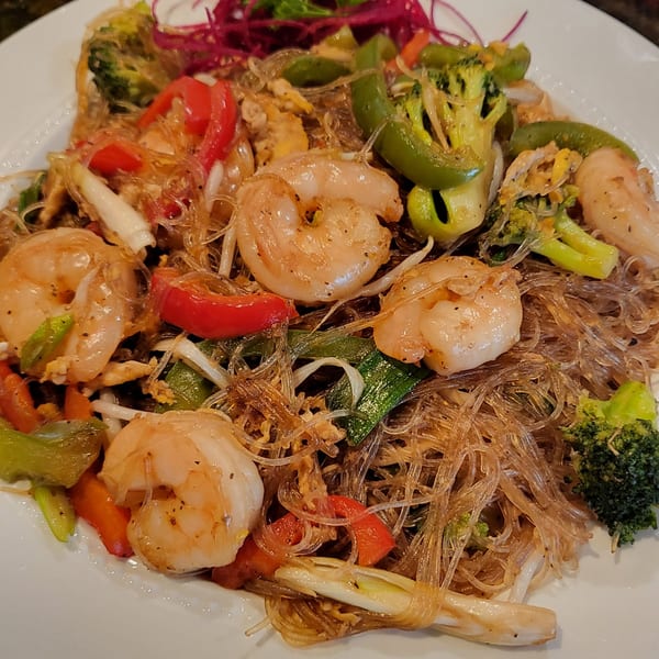 Close-up of Thai glass noodles with shrimp, broccoli, red bell peppers, and green onions.