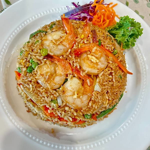 Shrimp fried rice with peas, carrots, and shredded cabbage on a white plate.